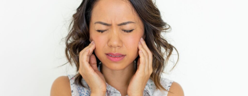 woman holding her jaw due to tmj pain and jaw tension at Majestic Dental in Cottleville, MO
